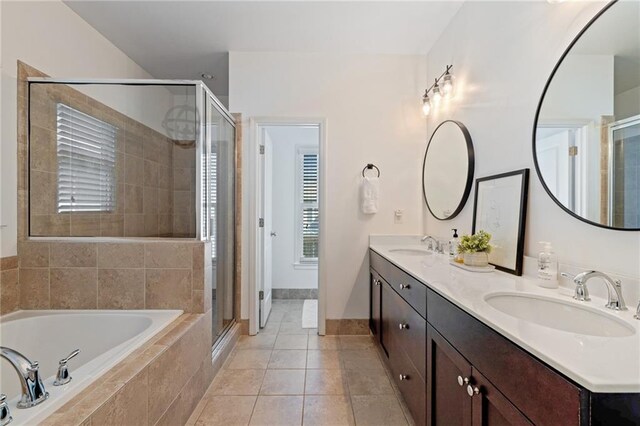 bathroom with a garden tub, a stall shower, double vanity, and baseboards
