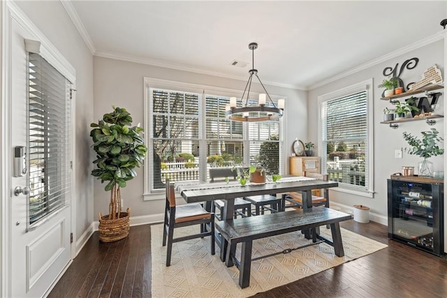 dining area with wine cooler, a chandelier, wood-type flooring, baseboards, and crown molding