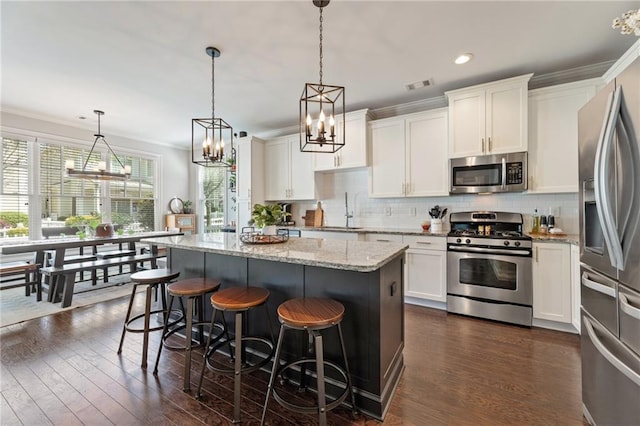 kitchen featuring stainless steel appliances, crown molding, a chandelier, white cabinets, and recessed lighting