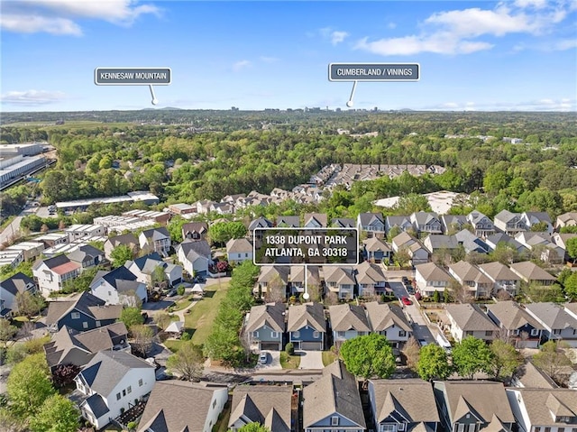 view of property location with nearby suburban area and a heavily wooded area