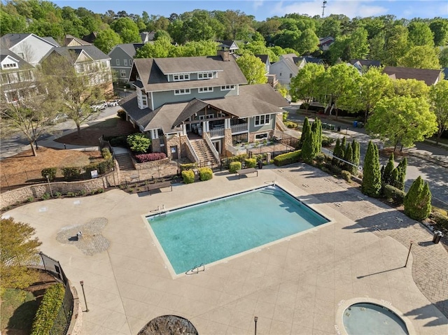 community pool featuring fence, a patio area, stairway, and a residential view