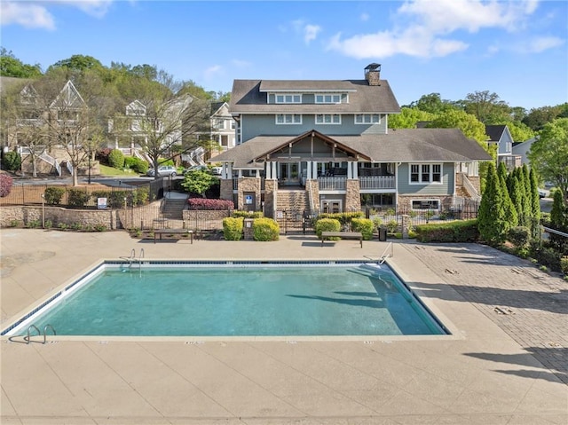community pool featuring fence, a patio, and stairs