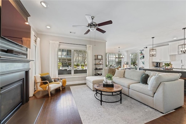 living room featuring a glass covered fireplace, plenty of natural light, a ceiling fan, a chandelier, and recessed lighting