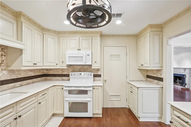 kitchen with white appliances, tasteful backsplash, sink, cream cabinetry, and light hardwood / wood-style flooring