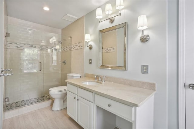 bathroom featuring vanity, toilet, and a shower with door