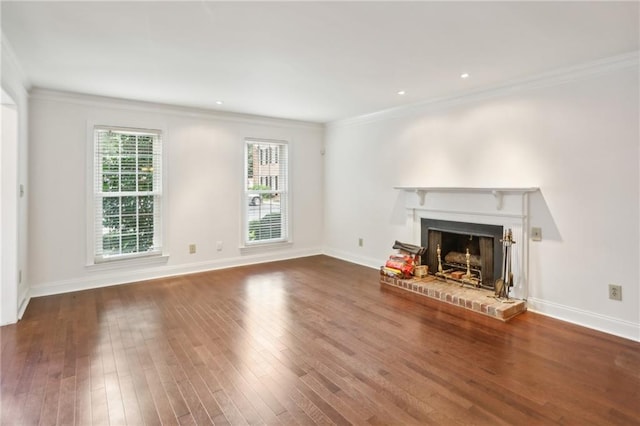 unfurnished living room featuring ornamental molding, a healthy amount of sunlight, hardwood / wood-style flooring, and a brick fireplace