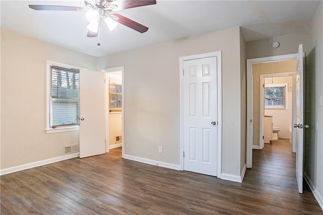 unfurnished bedroom featuring connected bathroom, a closet, dark hardwood / wood-style floors, and ceiling fan