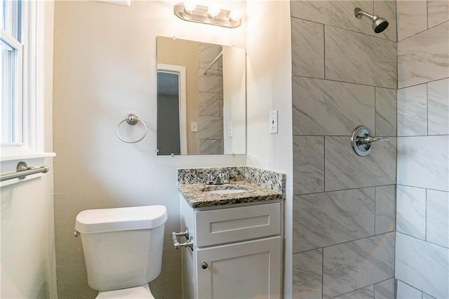 bathroom featuring vanity, a tile shower, and toilet