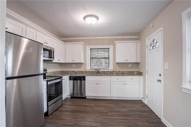 kitchen with sink, stone countertops, dark hardwood / wood-style floors, stainless steel appliances, and white cabinets