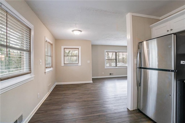 kitchen with a textured ceiling, stainless steel fridge, dark hardwood / wood-style floors, and white cabinets