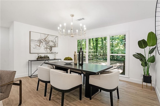 dining room featuring light wood-style flooring, visible vents, baseboards, and a notable chandelier