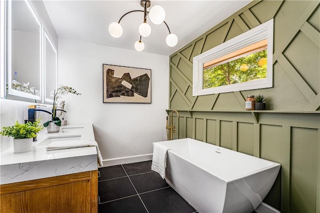 bathroom with a chandelier, double vanity, a freestanding bath, baseboards, and tile patterned flooring