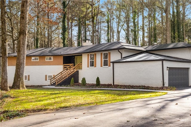 ranch-style home with a front lawn, a chimney, a garage, stairs, and stucco siding