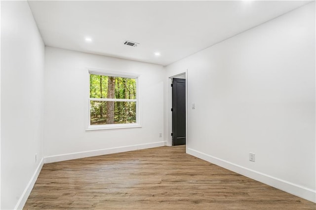 spare room featuring baseboards, wood finished floors, visible vents, and recessed lighting
