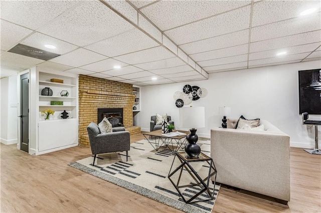 living room featuring baseboards, recessed lighting, built in features, wood finished floors, and a fireplace