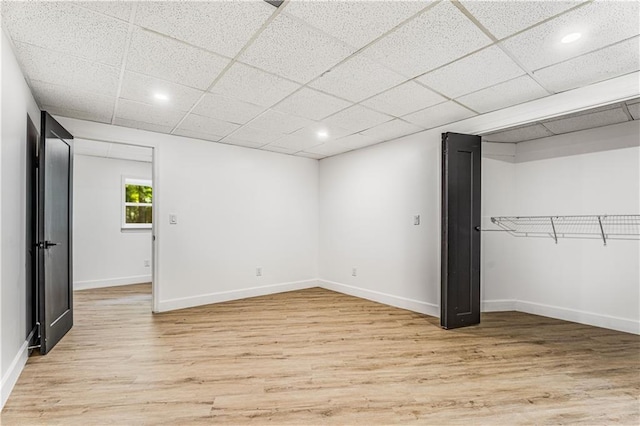 unfurnished bedroom with light wood-type flooring, a paneled ceiling, baseboards, and recessed lighting
