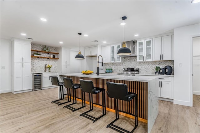 kitchen with wine cooler, a sink, light wood-type flooring, decorative backsplash, and stainless steel range with electric stovetop