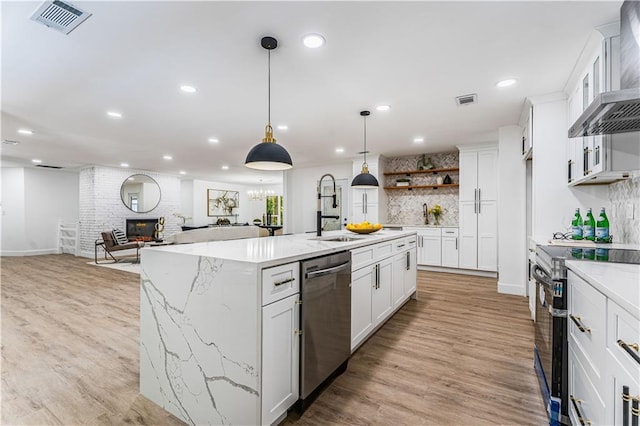 kitchen with range with electric cooktop, a sink, visible vents, wall chimney range hood, and dishwasher