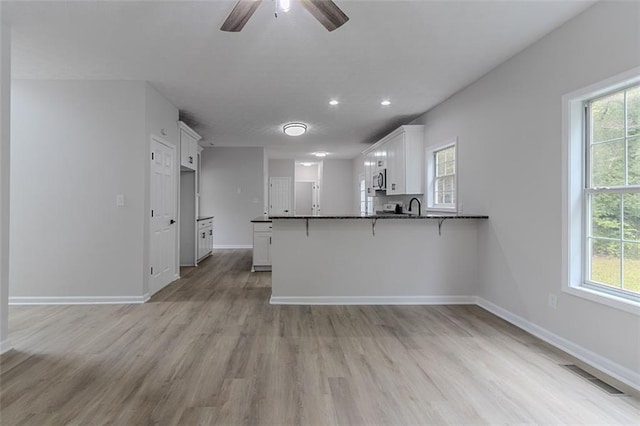 1706 Brandon Lee Way SW, Marietta, GA 30008 - kitchen featuring white cabinetry, a peninsula, light wood-type flooring, a ceiling fan, and a breakfast bar area