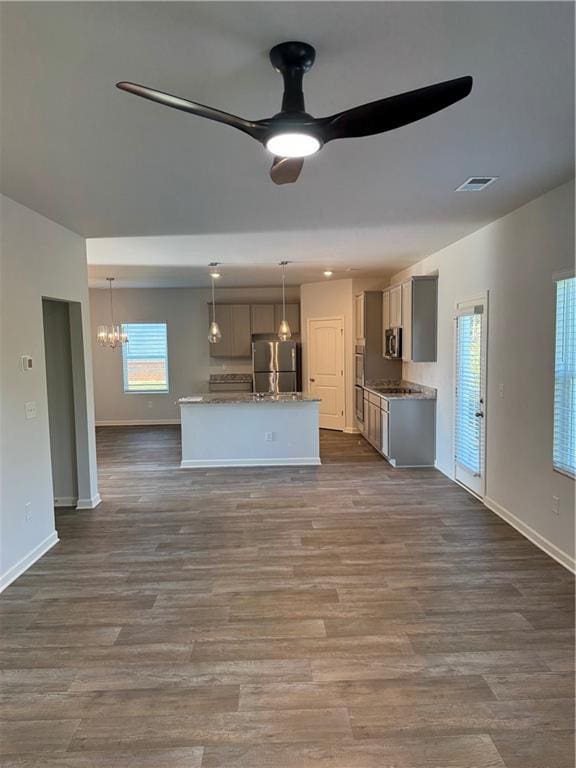 kitchen with pendant lighting, dark hardwood / wood-style flooring, stainless steel appliances, and ceiling fan with notable chandelier