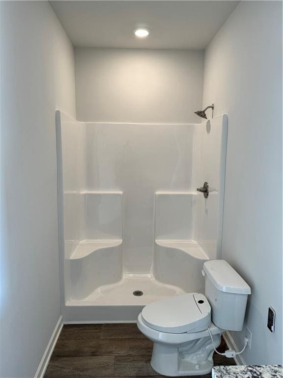 bathroom featuring walk in shower, toilet, and hardwood / wood-style flooring