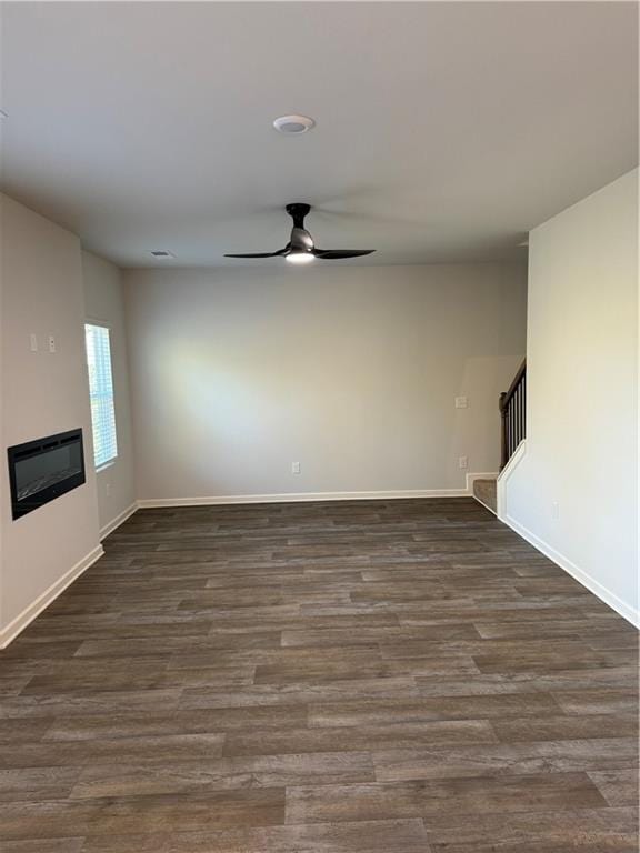 unfurnished living room featuring ceiling fan and dark hardwood / wood-style floors