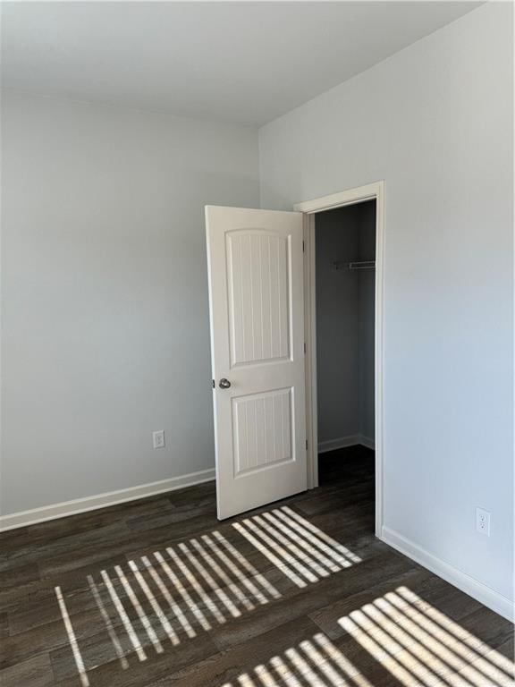 unfurnished bedroom featuring dark hardwood / wood-style floors and a closet