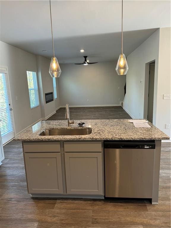 kitchen with dark hardwood / wood-style flooring, light stone counters, sink, pendant lighting, and dishwasher