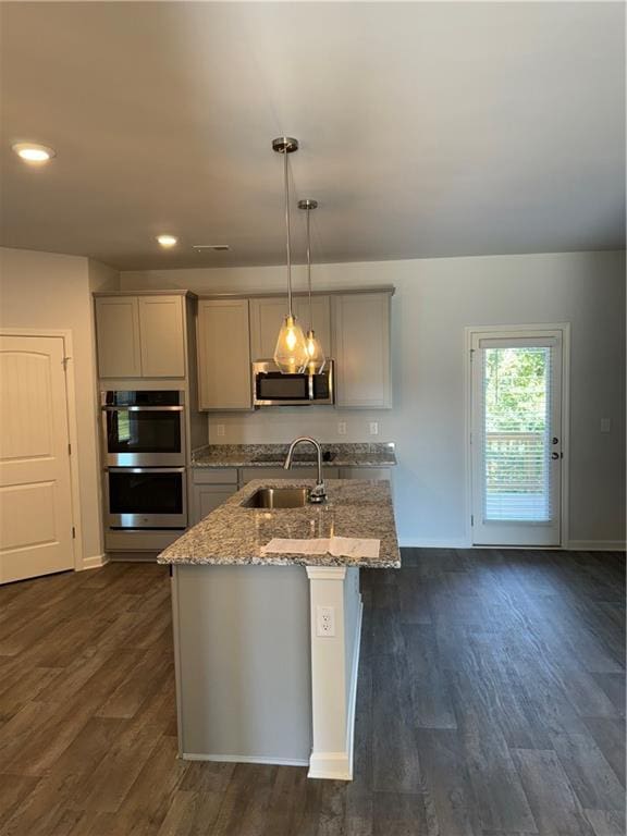 kitchen with dark hardwood / wood-style flooring, stainless steel appliances, sink, pendant lighting, and gray cabinets