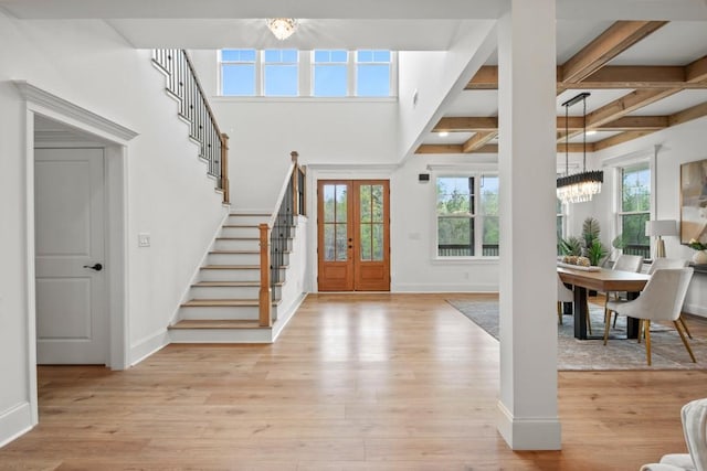 foyer entrance with beamed ceiling, light wood finished floors, baseboards, stairs, and an inviting chandelier