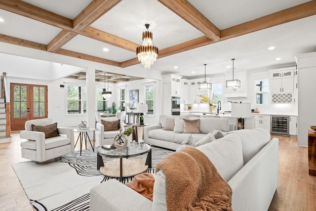 living room featuring light wood-style flooring, a wealth of natural light, beamed ceiling, and wine cooler
