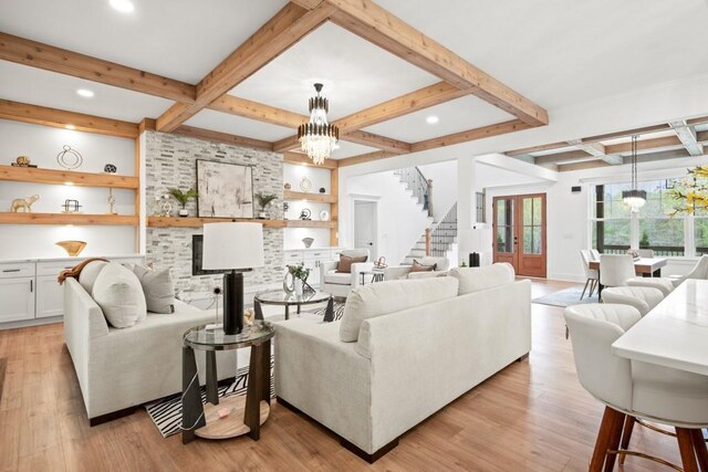 living room with a notable chandelier, coffered ceiling, light wood-style floors, and stairway