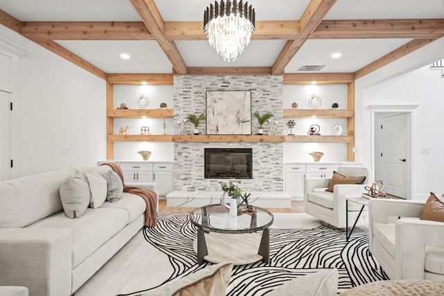 living area with coffered ceiling, a glass covered fireplace, visible vents, built in features, and beamed ceiling