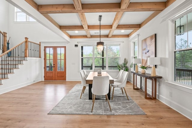 dining area featuring plenty of natural light, light wood-type flooring, coffered ceiling, and stairway