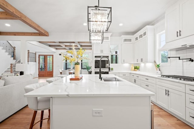kitchen with open floor plan, an inviting chandelier, beamed ceiling, and appliances with stainless steel finishes