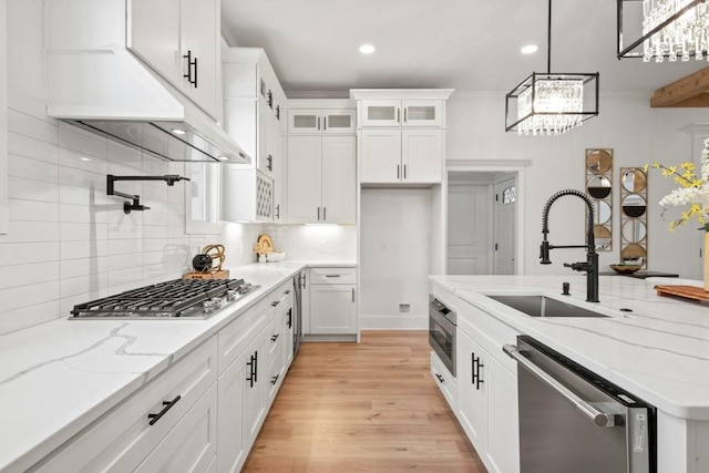 kitchen with tasteful backsplash, appliances with stainless steel finishes, glass insert cabinets, white cabinetry, and a sink