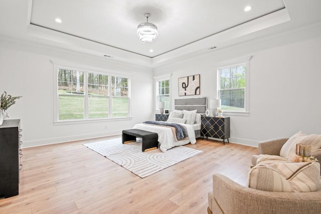bedroom featuring a tray ceiling, baseboards, and light wood finished floors