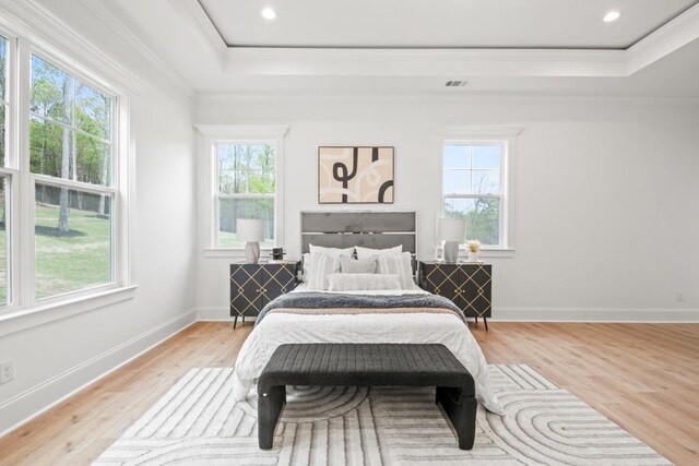 bedroom with a tray ceiling, multiple windows, and crown molding