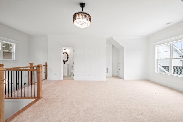 spare room featuring ornamental molding, light carpet, a notable chandelier, and visible vents