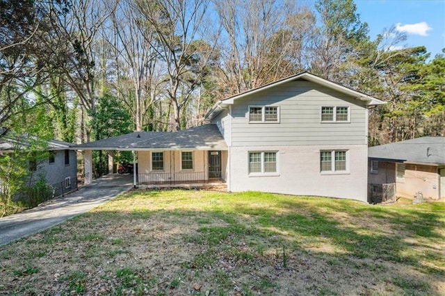 rear view of property with a carport, a yard, brick siding, and driveway