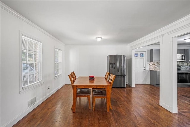 dining space featuring visible vents, ornamental molding, baseboards, and dark wood-style flooring