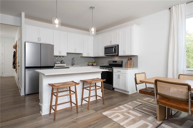 1714 Gunnin Trce NW, Atlanta, GA 30318 - kitchen featuring appliances with stainless steel finishes, tasteful backsplash, white cabinetry, a center island, and light countertops