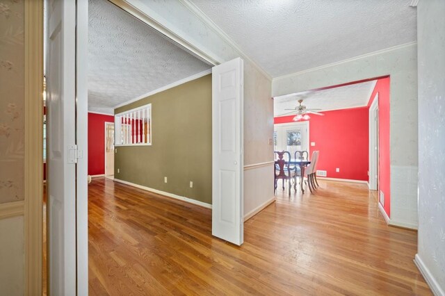 corridor with hardwood / wood-style flooring, a textured ceiling, and ornamental molding