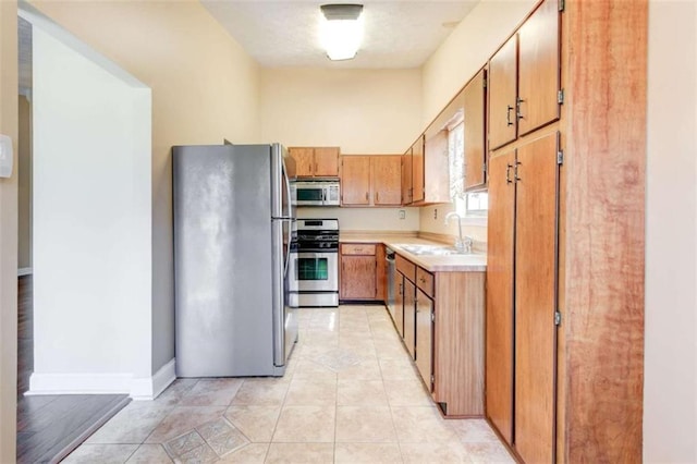 2211 Jonathan Ave, Lithonia, GA 30058 - kitchen featuring stainless steel appliances, light countertops, a sink, brown cabinets, and light tile patterned flooring