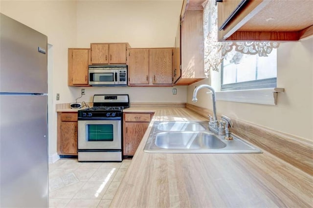 2211 Jonathan Ave, Lithonia, GA 30058 - kitchen featuring stainless steel appliances, a sink, light countertops, light tile patterned flooring, and brown cabinetry