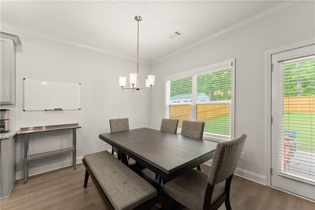 dining room featuring light wood-style flooring, a chandelier, crown molding, and baseboards