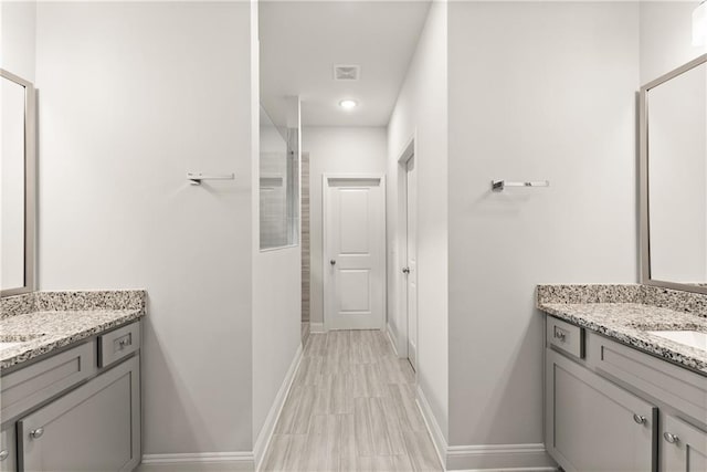 full bath with walk in shower, two vanities, baseboards, and recessed lighting