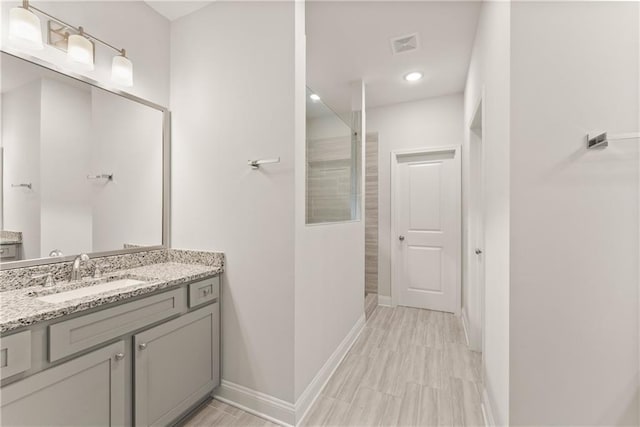 full bath featuring vanity, walk in shower, baseboards, and recessed lighting