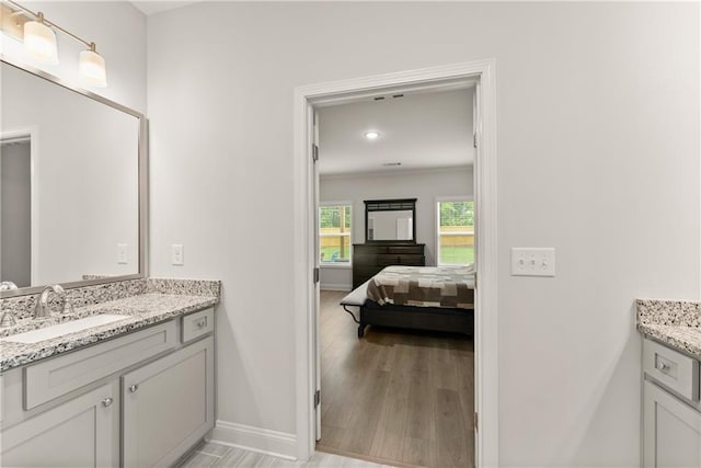 bathroom featuring baseboards, vanity, wood finished floors, recessed lighting, and connected bathroom