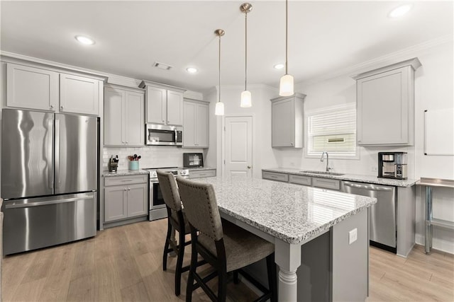 kitchen with appliances with stainless steel finishes, gray cabinets, a sink, backsplash, and light stone counters